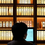 **A visual representation of someone poring over digitized Korean genealogical records, illuminated by the glow of a computer screen. The setting is a traditional Korean library, with shelves filled with ancient texts. Focus on the individual's determined expression as they decipher classical Chinese characters. Consider adding subtle elements of modern technology juxtaposed with the historical backdrop.**
